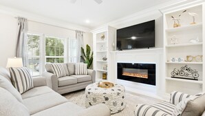 A living room with a fireplace, sofa, and TV. - BeachView-Arcade-Walk to Beach-Restaurants-Casino (Gulfport)