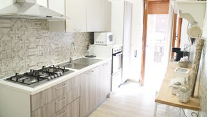 Een keuken met een gasfornuis, magnetron en kasten.