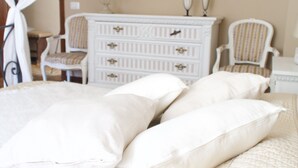 Een slaapkamer met een bed, twee stoelen, een dressoir en een lamp.