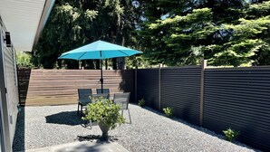A patio area with a blue umbrella, a table with chairs, and a potted plant. - Private Guest House  -Villa in the Valley- (Nanaimo)