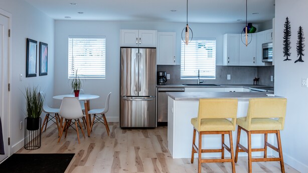 A modern kitchen with a stainless steel refrigerator, white cabinets, and a central island with bar stools. - Private Guest House  -Villa in the Valley- (Nanaimo)