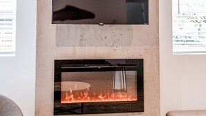 A modern living room with a flat-screen TV mounted above a fireplace. - Private Guest House  -Villa in the Valley- (Nanaimo)