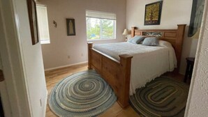 Une chambre à coucher avec un lit en bois, une fenêtre et un ventilateur de plafond.