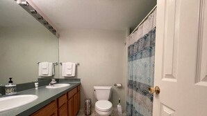 Une salle de bain avec deux lavabos, des toilettes et un rideau de douche.