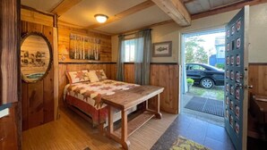 Ein Zimmer aus Holz mit einem Bett, einem Tisch und einer Tür mit Ziel-Design.