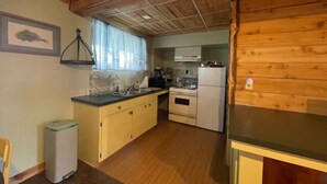 Eine kleine Küche mit Holzausstattung, inklusive Kühlschrank, Backofen und Spüle.