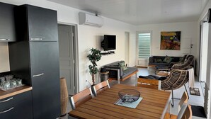Eine moderne Küche mit Essbereich, einem an der Wand montierten Fernseher und einem Gemälde.