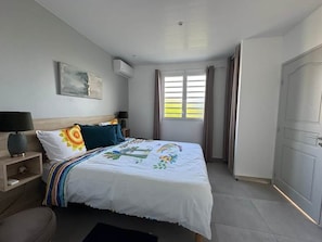 Une chambre à coucher comprenant un lit, des tables de chevet, une commode, une chaise, une fenêtre avec des rideaux et une porte.