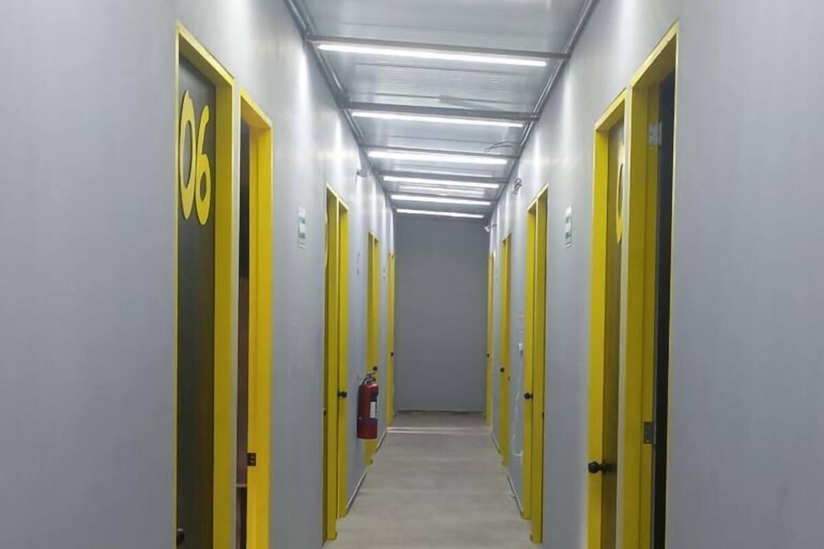 Un long couloir étroit, avec des portes de chaque côté, chacune portant un numéro.
