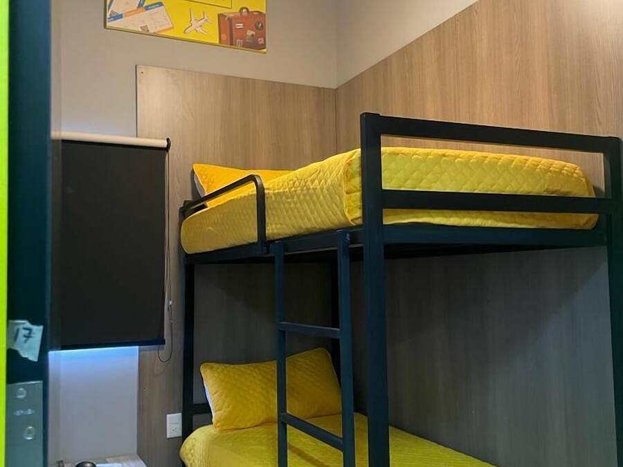 A bunk bed room with a ceiling fan, a small table, and a wall-mounted TV.