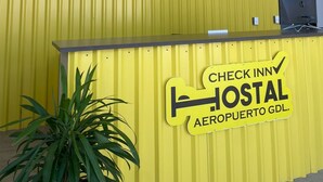Un mostrador de recepción amarillo con un cartel que dice "Check Inn Hostal Aeropuerto GDL".