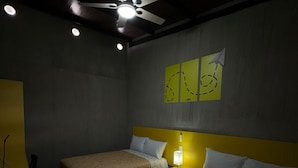 Habitación de hotel con dos camas, ventilador de techo y decoración en las paredes.