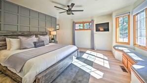 A bedroom with a large bed, a ceiling fan, a window with curtains, and a built-in bench by the window. - Spacious Flagstaff Home w/ Hot Tub & Grill! (Flagstaff)