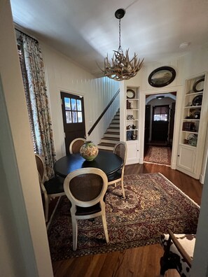 A dining area with a black table, two chairs, a decorative vase, and a chandelier. - Quirky historic home, fully renovated! Designer interior! Plush linens! Firepit! (New Iberia)