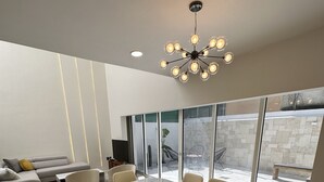 Zona pranzo moderna con tavolo e sedie in marmo, una poltrona e un'ampia finestra vista all'esterno.
