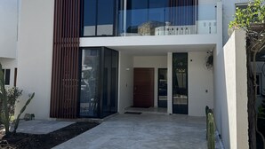 Una moderna casa a due piani con ampie finestre, un balcone e un vialetto in cemento.