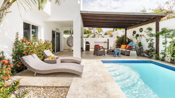 A modern outdoor pool area with lounge chairs, a pergola, and a barbecue setup. - Private villa with pool, enjoy the Dominican Caribbean. (Cabarete)
