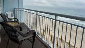 A balcony with wicker chairs overlooking a beach.
