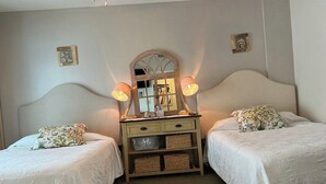 A bedroom with two single beds, a dresser with baskets, and a mirror above the dresser.