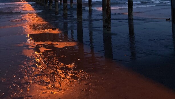 A pier extending into the water with street lamps along its length.