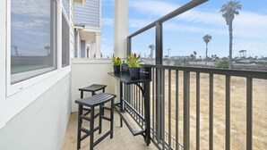 A balcony with a view of palm trees and a building in the background. - Silver Strand Beach Bungalow (Imperial Beach)