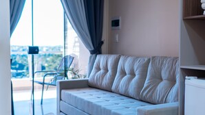 Un salon moderne avec un canapé, un fauteuil et une vue sur l’extérieur.