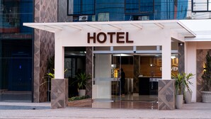 L’entrée d’un hôtel au design moderne, avec une porte en verre et une enseigne indiquant « HÔTEL ».