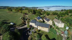 An aerial view of a rural property with stone buildings, a driveway, and surrounding greenery. - Gîtes de France 6 people in Le Teil (ALBARET LE COMTAL)