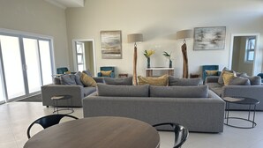 A spacious living room with a grey sofa set, a round wooden table, and modern lamps. - Seamist Holiday home, Spectacular Mountain View, walk to pool gym restaurant (Lucea)