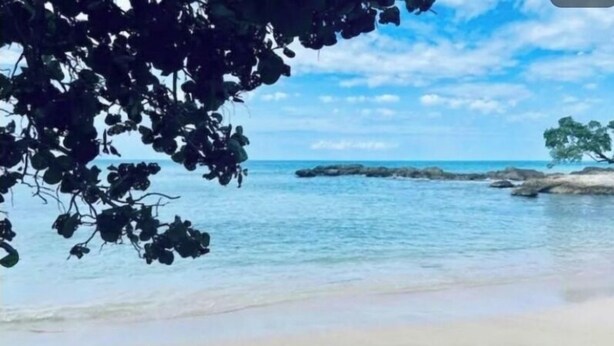 A beach with clear water, a sandy shore, and a rocky outcrop in the distance. - Seamist Holiday home, Spectacular Mountain View, walk to pool gym restaurant (Lucea)