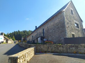 A stone building with a sloped roof, a small balcony, and a stone wall in front. - Le Bes, at La Chaldette (LA CHALDETTE)