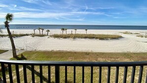 A beach view from a balcony with a railing, palm trees, and a clear sky. - #113 Beautiful 2 bed 2 bath condo with beach views (Pass Christian)