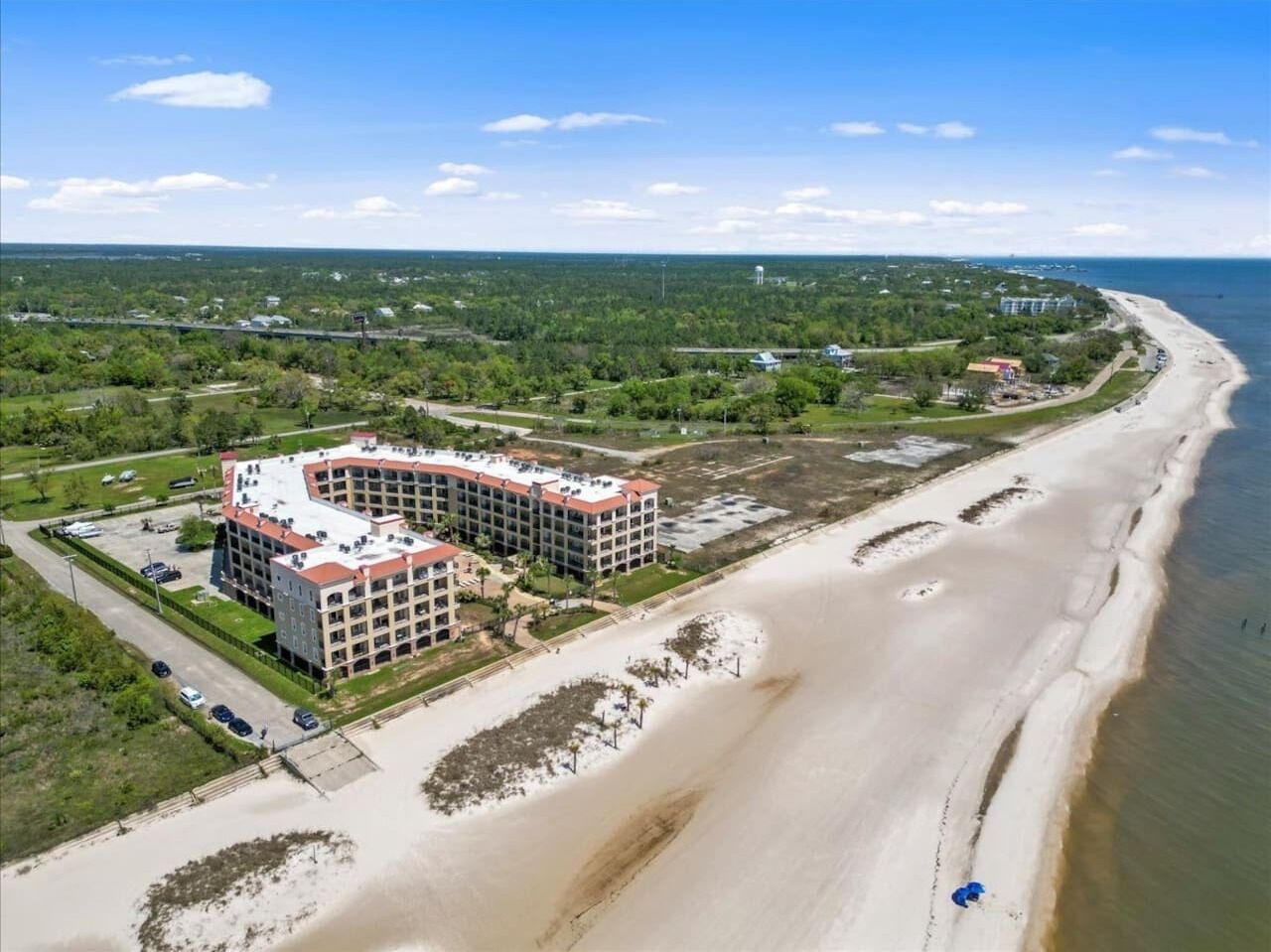 A coastal hotel with a curved building, beachfront access, and a view of the ocean.