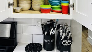 Ett köksskåp med flera hyllor där tallrikar, skålar och köksredskap förvaras.