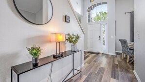 A modern entryway with a console table, a mirror, a lamp, and a potted plant.