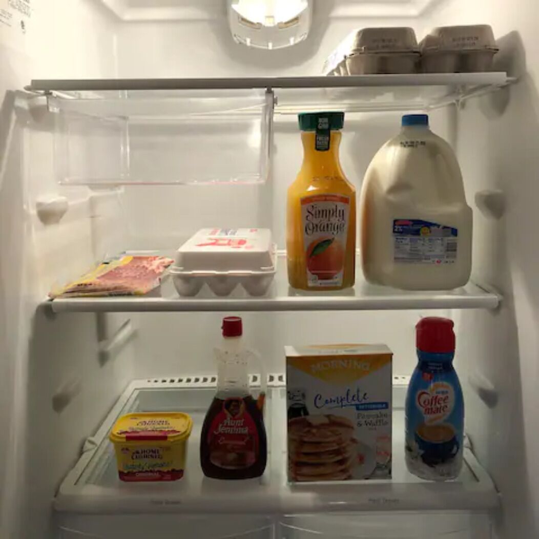 Un frigorifero pieno di generi alimentari assortiti, tra cui latte, succo d'arancia, uova e caffè.