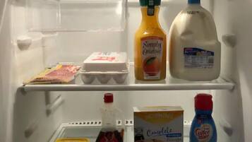 Un réfrigérateur rempli de divers aliments, notamment du lait, du jus d’orange, des œufs et du café.