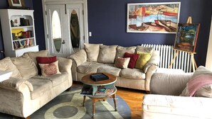 Una sala de estar con un sofá color beige, una mesita redonda y una estantería.