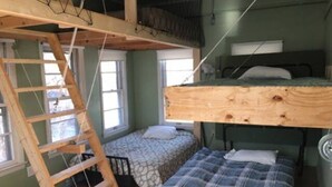 Una habitación con literas, una escalera y una ventana.