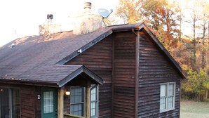 Puinen mökki, jossa on kuisti, savupiippu ja satelliittiantenni.