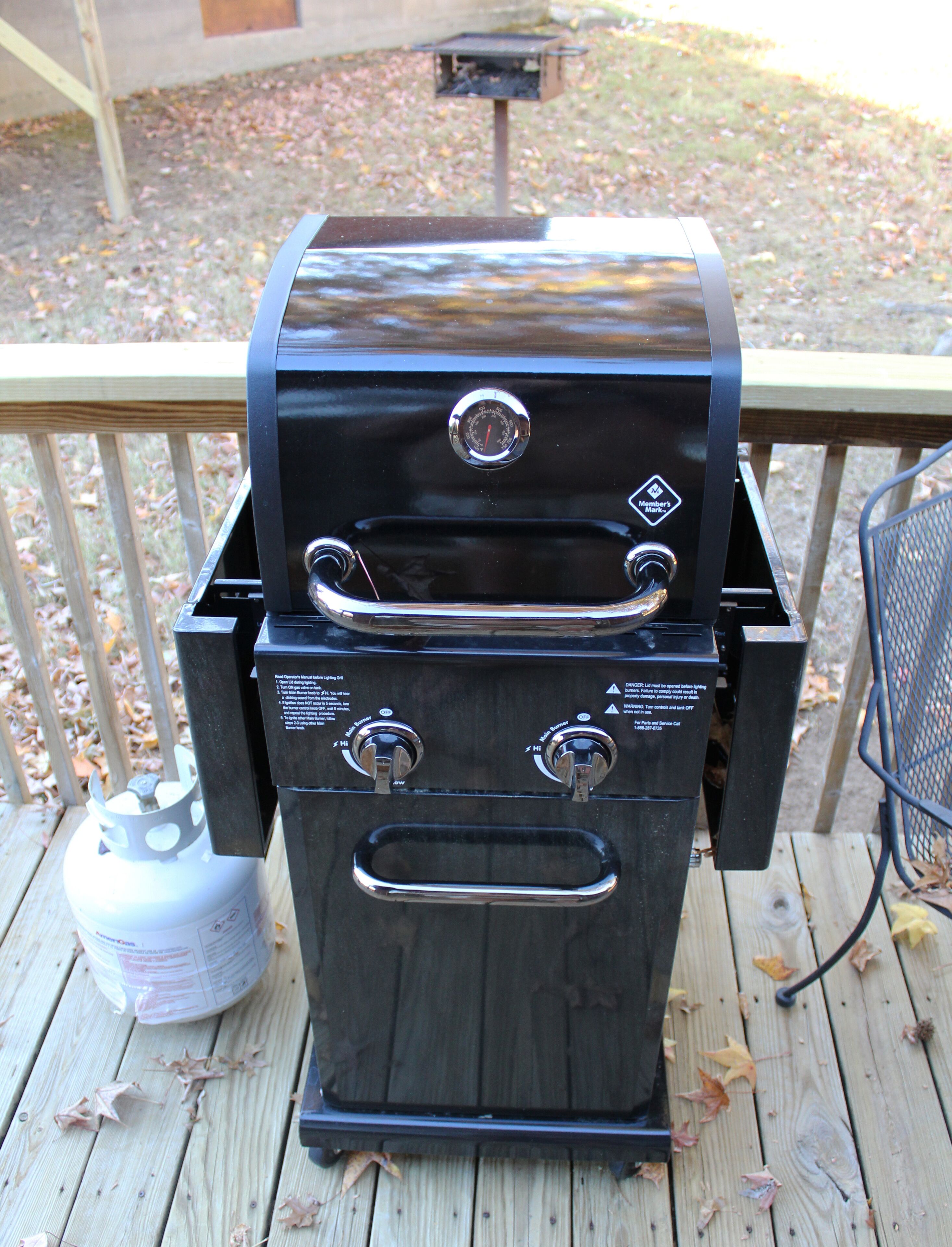 Un barbecue doté de deux boutons de réglage, d’un réservoir de combustible et d’un couvercle de gril en métal.