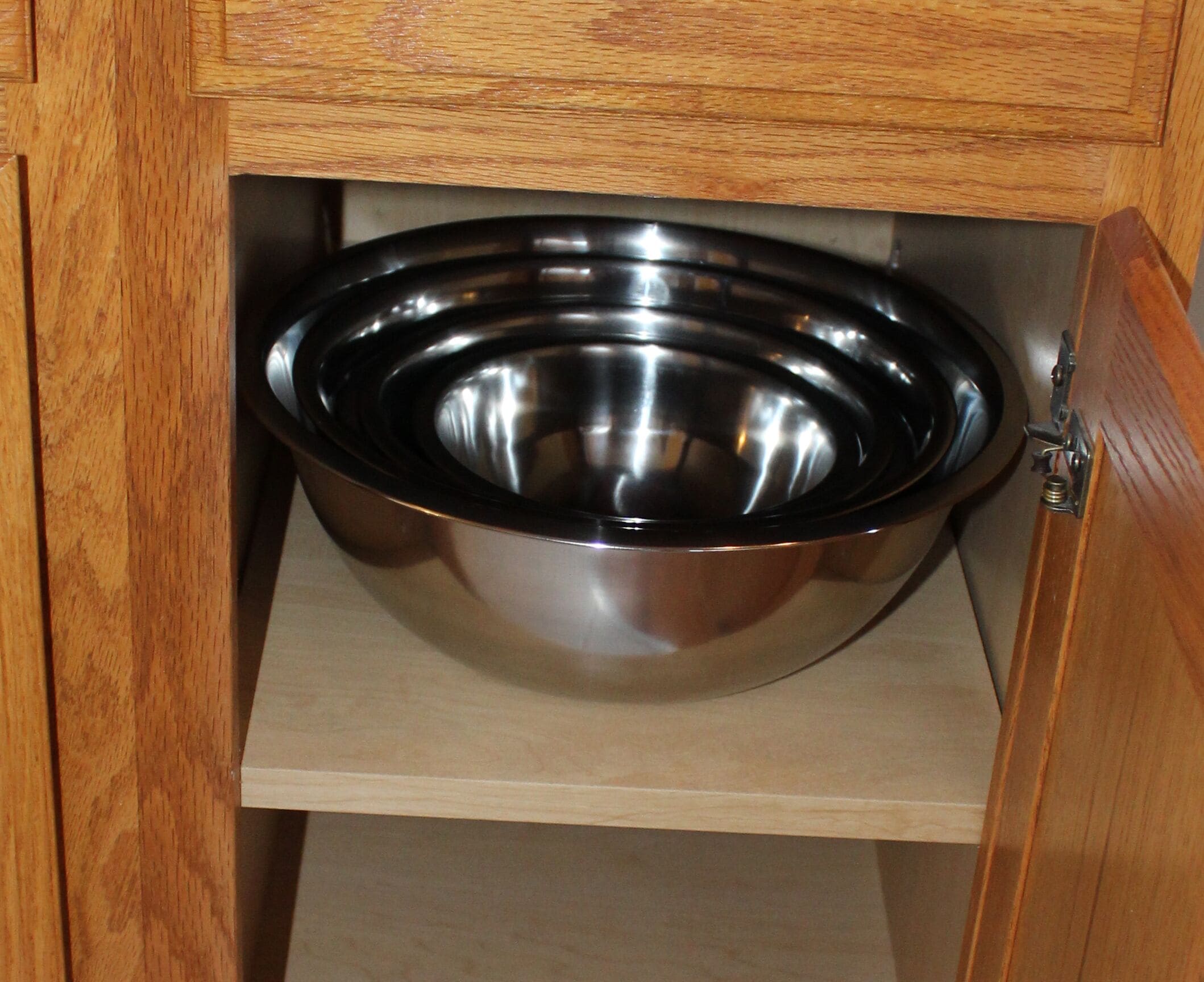 Una ciotola in acciaio inox all'interno di un mobile in legno.
