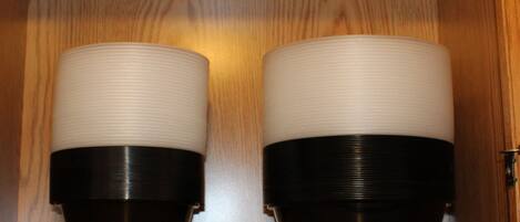Deux objets cylindriques à la surface striée, placés côte à côte dans un meuble en bois.