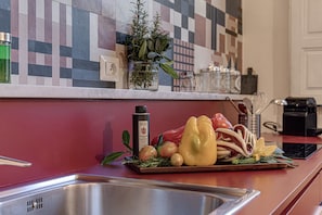Una encimera de cocina con diversos vegetales frescos, una botella y una planta en maceta.