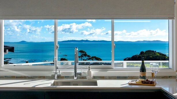 A kitchen with a large window overlooking a coastal view.