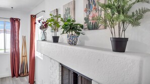 Una sala de estar con chimenea, plantas en macetas y obras de arte en la pared.