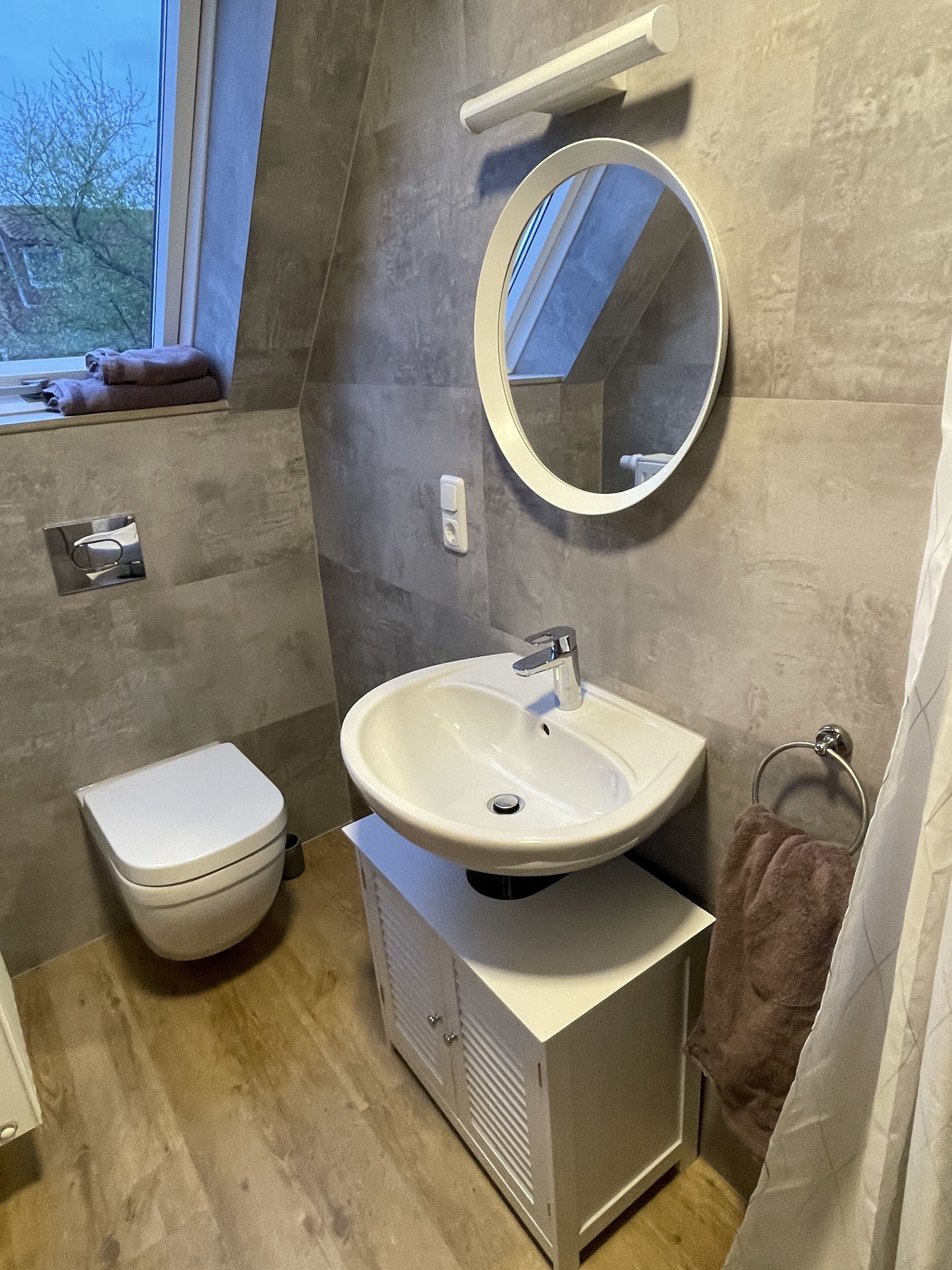 A bathroom with a toilet, sink, mirror, and towel rack.