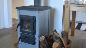 Ein Holzofen mit einem Korb Brennholz daneben.