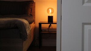 Ein Schlafzimmer mit einem Bett, einem Nachttisch mit Lampe und einer Tür.