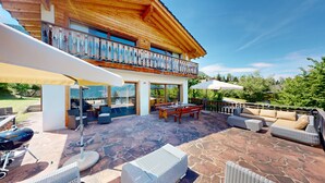Ein Holzhaus mit Balkon, Sitzgelegenheiten im Freien und einer Steinterrasse.